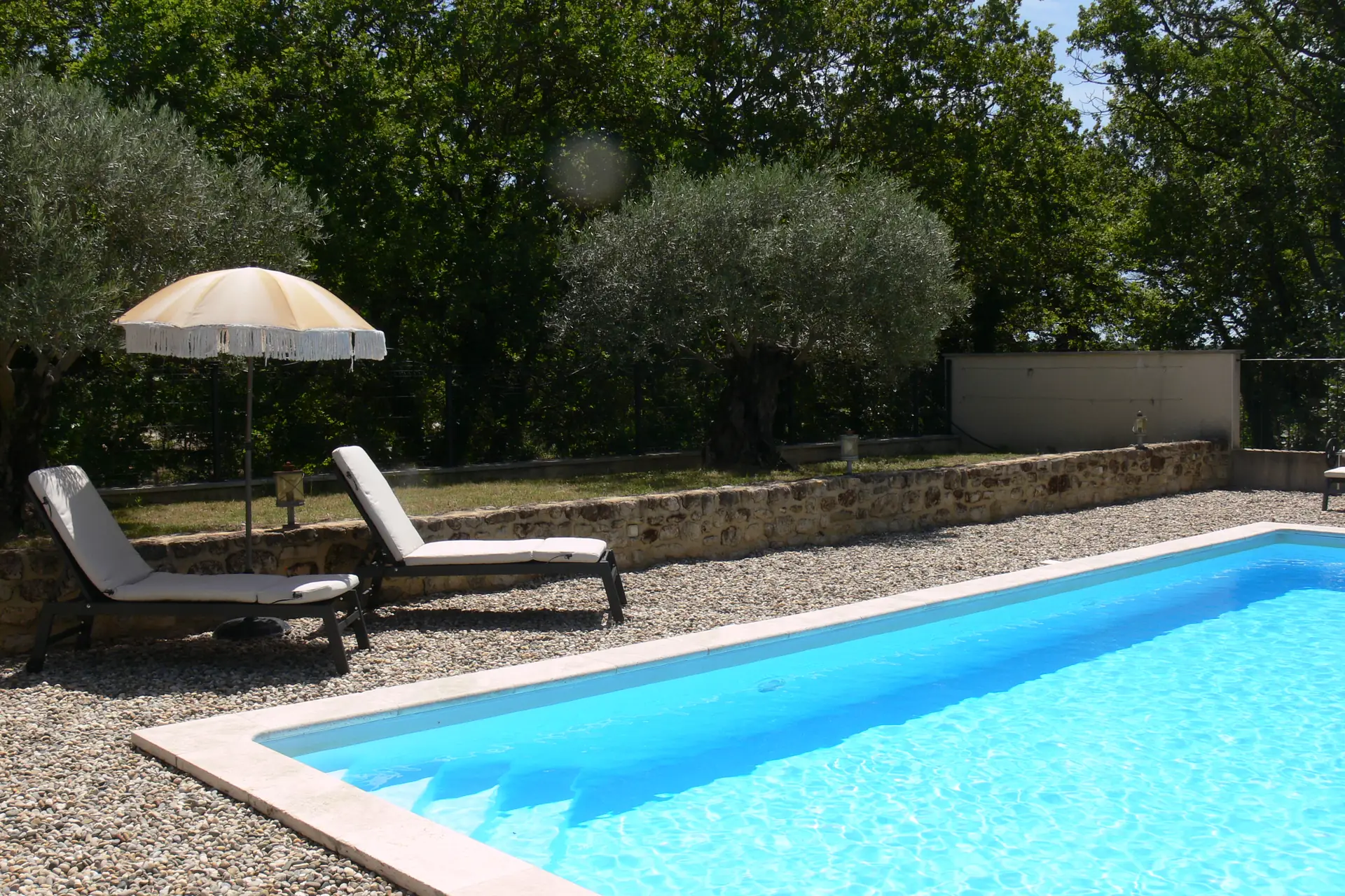Transats avec matelas et parasol au bord de la piscine de La Romagnolette